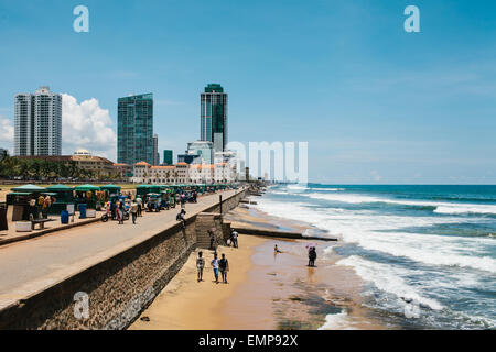 People walk along the seafront at Galle Face Green in Colombo's capital city, Sri Lanka, with Galle Face Hotel in the background Stock Photo