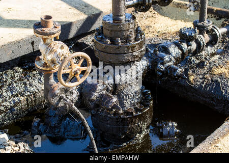 Greasy oil pipes leaking oil and polluting environment at an oil extraction site Stock Photo