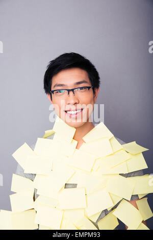 Smiling asian man in glasses pasted stickers over gray background. Looking at camera Stock Photo