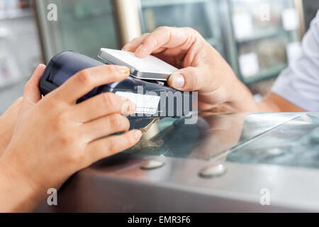 Customer Making Payment Through Smartphone In Butchery Stock Photo