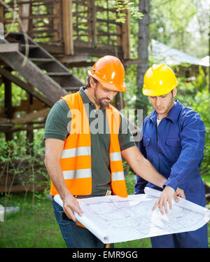 Architect Explaining Blueprint To Colleague Stock Photo