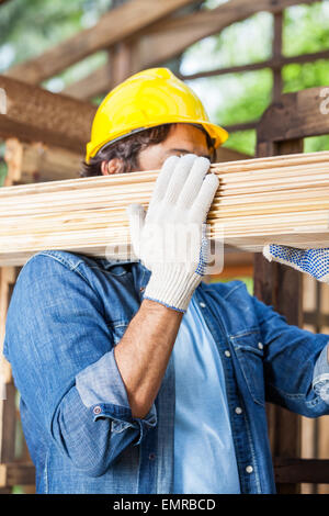 Worker Carrying Wooden Planks At Site Stock Photo
