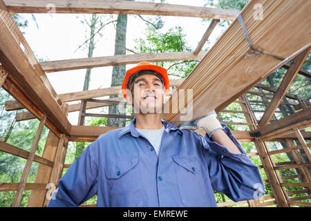 Smiling Construction Worker Carrying Wooden Planks Stock Photo