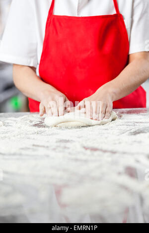 Chef Kneading Dough At Messy Counter Stock Photo