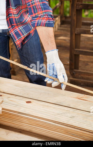 Construction Worker Measuring Timber With Tape Stock Photo