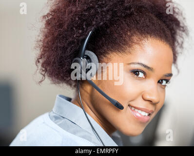 Confident Female Customer Service Agent Wearing Headset At Desk Stock Photo
