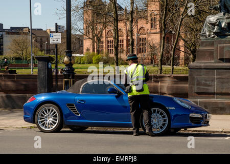 A parking attendant issuing a parking ticket on Kelvin Way, Glasgow, Scotland, UK Stock Photo