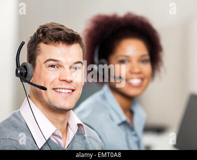 Customer Service Representative With Colleague Working In Office Stock Photo