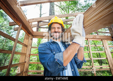 Construction Worker Carrying Wooden Planks On Shoulder Stock Photo