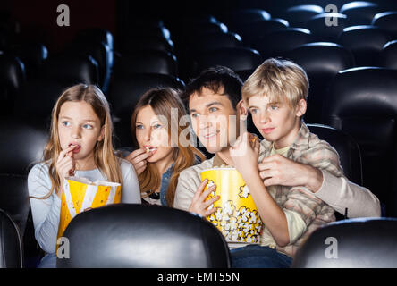 Family Eating Popcorn While Watching Film In Theater Stock Photo