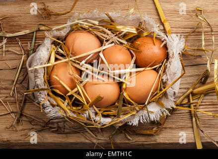 Eggs in hay on wooden background Stock Photo