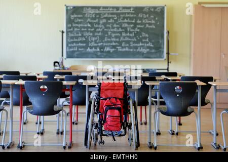 A wheelchair standing between other chairs in a school classroom./picture alliance Stock Photo