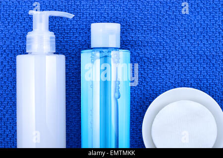 Daily cleansing cosmetics - face wash cleansing gel, smoothing toner and cotton cleansing pads on navy blue towel. Stock Photo