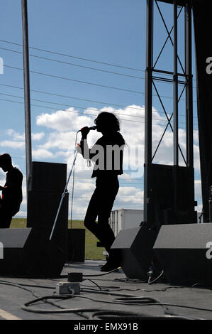 Generic or anonymous, singer with band, silhouetted against blue cloudy sky on outdoor festival concert stage. Stock Photo