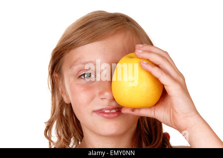 A young blond girl is playing with her yellow apple she likes to eat, isolated on white background. Stock Photo