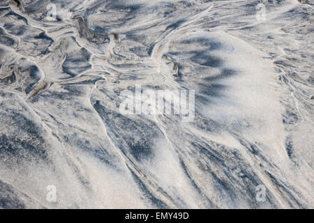 Grey and beige abstract background of wet sand texture formed by flowing water on beach Stock Photo