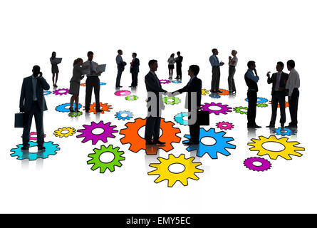 Silhouettes of group of busy business people standing on multi-colored gears. Stock Photo