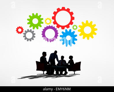 Silhouettes of Business People Having a Meeting and Gears Above Stock Photo