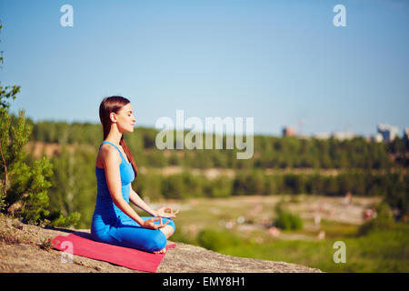 Meditating woman practicing yoga outdoors Stock Photo