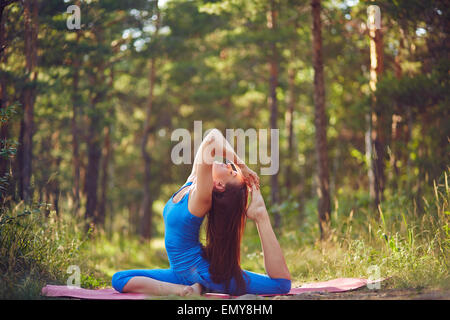 Active young woman doing stretching exercise in park or forest Stock Photo