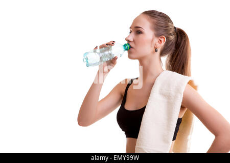 Woman after sport drinking water from bottle with towel on shoulder isolated over white background Stock Photo