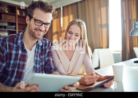 Young employee and his colleague using modern gadgets in business Stock Photo