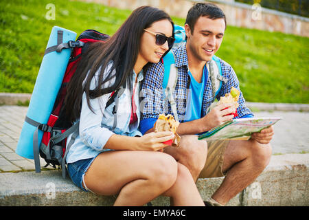 Young man and woman with rucksacks and map choosing travel route Stock Photo
