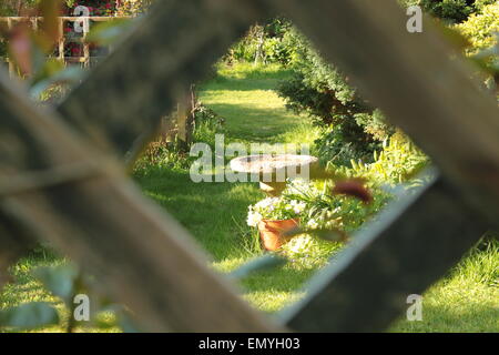 view of bird table framed by diamond trellis in a garden on a sunny summer day Stock Photo