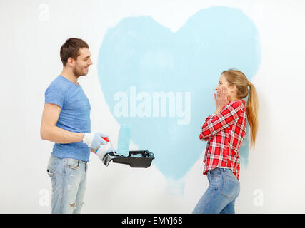 smiling couple painting big heart on wall Stock Photo