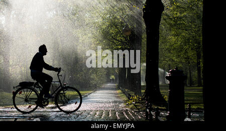 Berlin, Germany. 24th Apr, 2015. A man rides on his bicycle passing water sprinklers in the Tiergarten Park in Berlin, Germany, 24 April 2015. Photo: Lukas Schulze/dpa/Alamy Live News Stock Photo