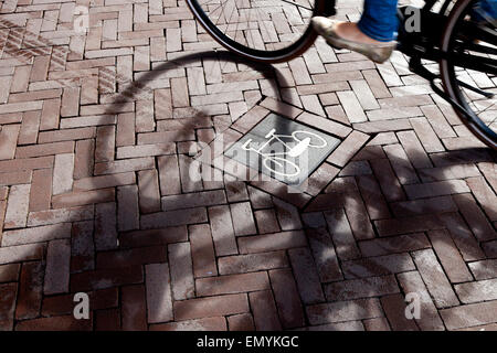 A bike sign on the road with the shadow of a cyclist going by, Rijksmuseum, Amsterdam, Netherlands Stock Photo