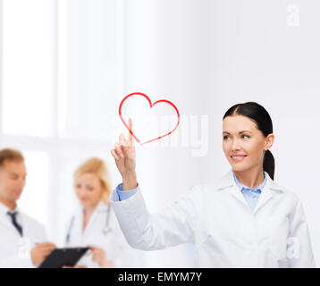 smiling female doctor pointing to heart Stock Photo