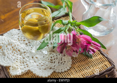 Sweet Japanese plum wine with fruit in glass photographed with beautiful pink wildflowers Stock Photo