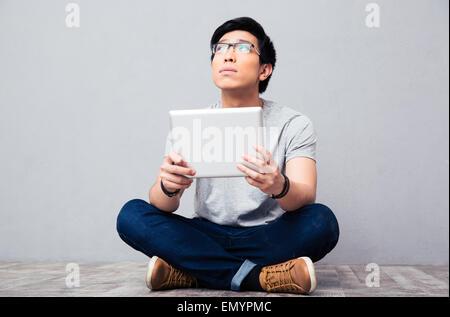 Young asian man sitting on the floor with tablet computer Stock Photo