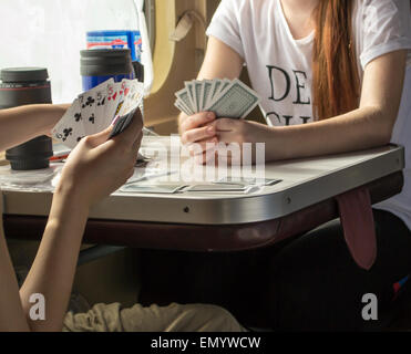 Two young women playing cards on a train Stock Photo