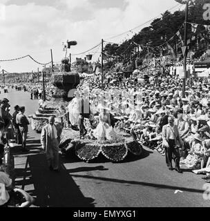 The annual Battle of Flowers carnival held on the Channel Island of Jersey. Crowds line the street to watch a procession. 5th August 1958 Stock Photo