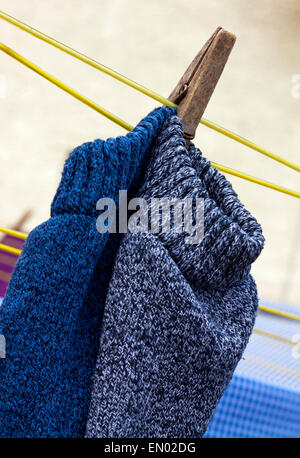 Wooden clothes peg on a washing line with socks hanging out to dry Stock Photo