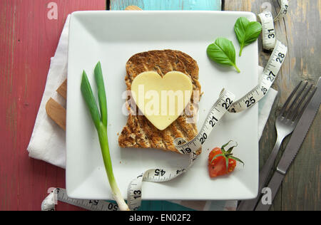 Heart shape slice of cheese on toasted whole grain bread Stock Photo