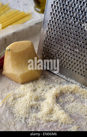 Close-up grated parmesan cheese and metal grater on wooden table. Stock Photo