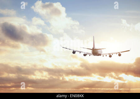airplane in sunset sky Stock Photo