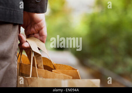 consumer basket, close up of paper shopping bags in male hand Stock Photo