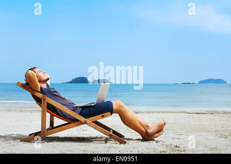 smiling businessman with computer relaxing on the beach Stock Photo