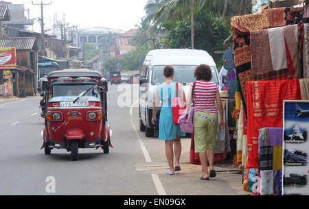 Sri Lanka: tourists walking on the road in Hikkaduwa with a tuk tuk passing Stock Photo