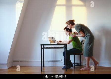 young couple looking at the laptop at their home in bright interior Stock Photo