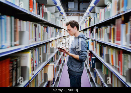 young student reading book between the shelves in the library Stock Photo
