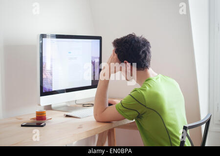 young man looking at the screen of computer at home interior Stock Photo