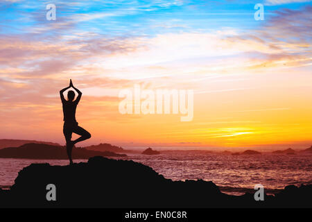beautiful silhouette of woman practicing yoga near the sea Stock Photo