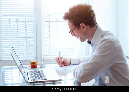 writing resume, young handsome business man working in office Stock Photo