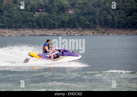 Young man riding jet boat on a summer day at the lake. Stock Photo