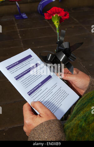 Preston, Lancashire, UK 25th April 2015. Woman with red rose & Pamphlet at the International Workers Memorial Day event with memorial service, March & rally to acknowledge those killed, injured and made ill through work each year.  The Commemoration and Campaign at Preston Flag market this year is to remember the dead and fight for the living with disease and illness generated by hazardous substances such as Asbestos. Stock Photo